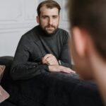 A thoughtful therapist listens attentively to a patient during a counseling session in a modern office.
